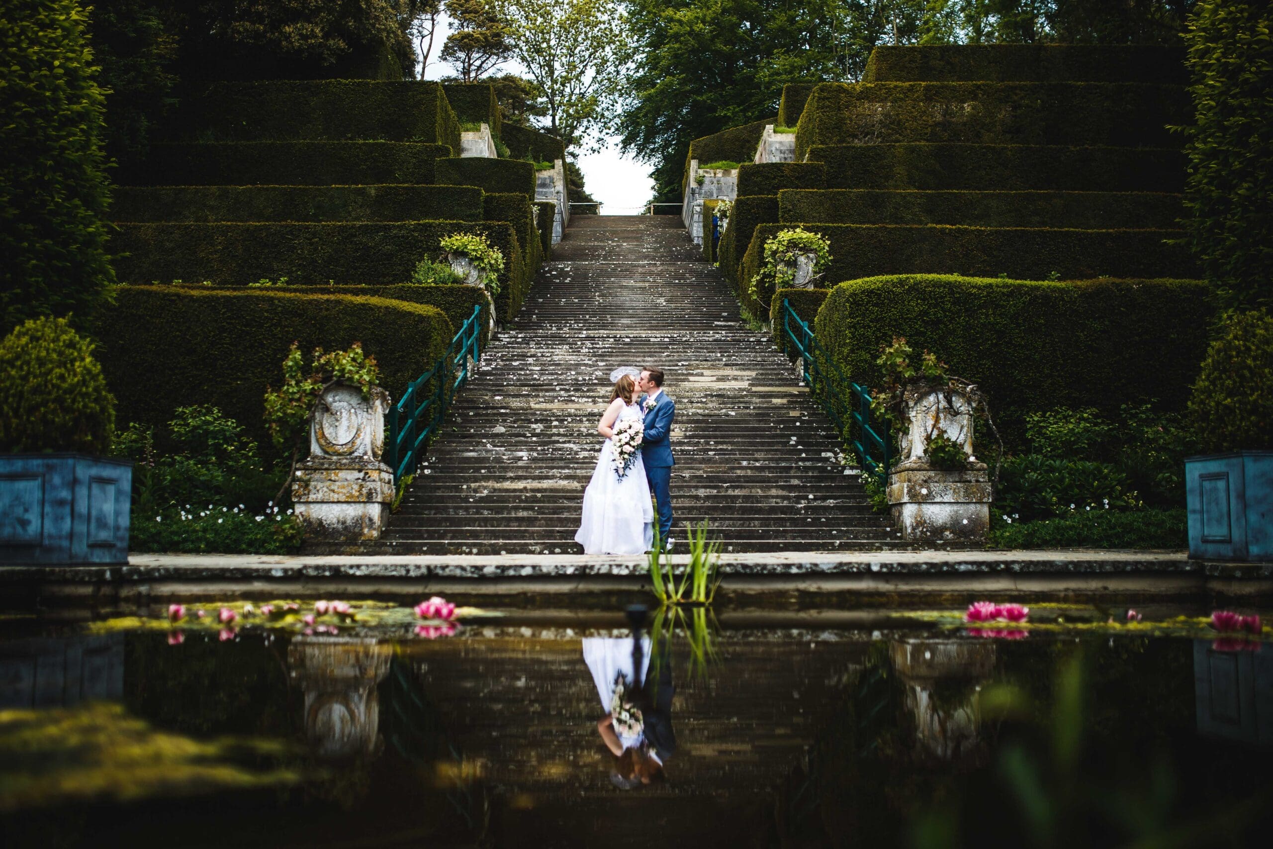 A bride and groom share a kiss at the bottom of the steps at Port Lymne Safari Park, at their beautiful kent wedding