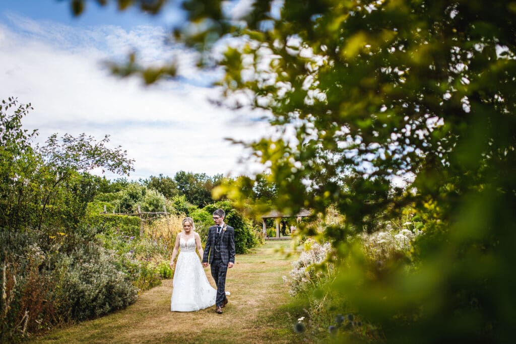 Bride and groom enjoying a quiet walk through The Gardens wedding venue in Kent, photographed by The Gardens wedding photographer